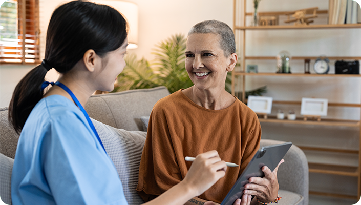 A home health nurse reviewing digital OASIS assessment documentation on a tablet with a patient to ensure compliant home health billing.