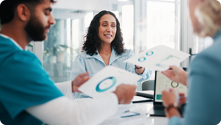 A business consultant sharing revenue charts and documentation with healthcare team members during an agency startup consultation.